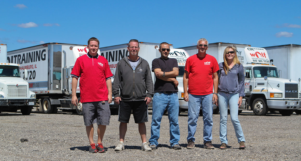 Group of CDL School instructors standing in front of training trucks