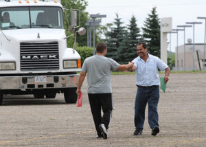 Two people celebrating passing their CDL exam next to a truck